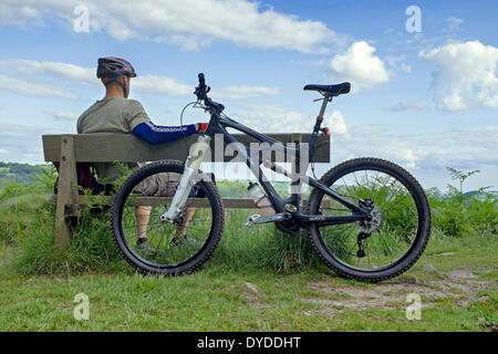 Vélo de montagne mâle posé sur un banc en bois. Banque D'Images