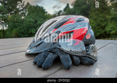 Tachés de boue casque de vélo avec des lunettes et des gants. Banque D'Images