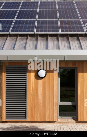 Des panneaux solaires sur toit de l'école contre les murs de bois vêtu. Banque D'Images