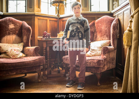 Un jeune garçon debout avec un livre sous le bras à Thornbury Castle. Banque D'Images