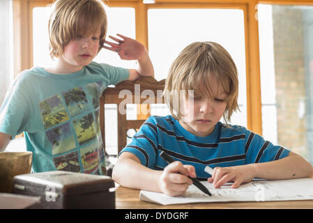 Un garçon de sept ans à la table de dessin. Banque D'Images