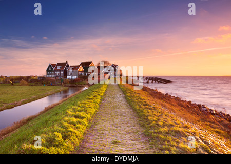 Petit village derrière une digue, photographié sur l'île de Marken dans les Pays-Bas au lever du soleil Banque D'Images