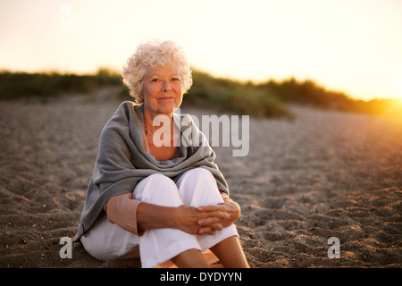 Portrait of happy vieille femme assis sur la plage. Dame de race blanche à la retraite de détente en plein air Banque D'Images