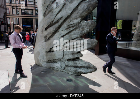 Les travailleurs de la ville par le passage de l'oeuvre d'un géant de l'aile de bronze lors d'un midi de printemps dans le quartier financier de Londres. Comme la lumière se reflète sur les immeubles de bureaux à proximité, la foule à l'heure du déjeuner devant ce géant des illustrations sur leur façon de réunions et sandwicheries. Les dix mètres de haut est la sculpture en bronze par le président de la Royal Academy of Arts, Christopher Le Brun, commandé par Hammerson en 2009. Elle est appelée 'La Ville' de l'aile et a été jeté par Morris Singer, fondateurs de l'art réputé pour être la plus ancienne fonderie d'art dans le monde. Banque D'Images