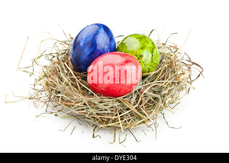 Rouge, vert et bleu dans les oeufs de pâques nid de foin sur fond blanc Banque D'Images