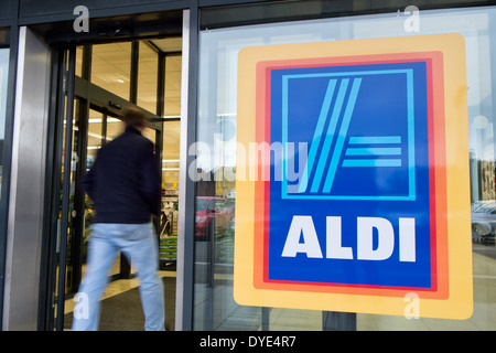 Un homme, mouvement floue, la marche dans une succursale d'Aldi supermarché pour acheter. Montrant le signe & identité du magasin Banque D'Images