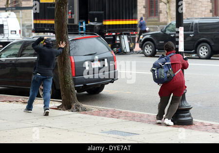 Boston, USA. Apr 15, 2014. Un homme est titulaire d'un arbre comme d'une femme est titulaire d'un lampadaire en grand vent et pluie à Boston, Massachusetts, États-Unis, 15 avril 2014. Credit : Yin Bogu/Xinhua/Alamy Live News Banque D'Images