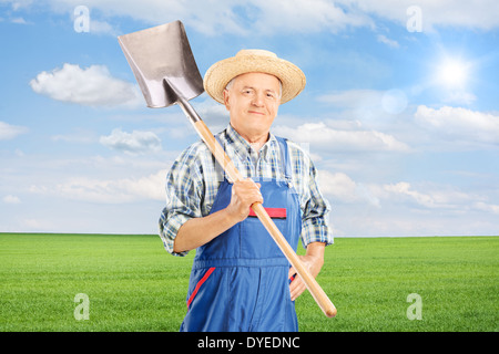 Travailleur agricole mature holding shovel in field Banque D'Images