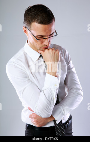 Portrait d'un homme réfléchi, dans les verres sur fond gris Banque D'Images