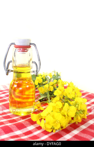 Une bouteille d'huile de colza et de fleurs de colza contre fond blanc Banque D'Images