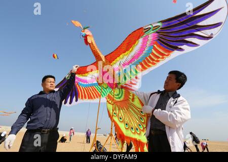 Shanghai, Chine, la province de Shandong. Apr 16, 2014. Un homme vole un cerf-volant en forme d'oiseaux lors d'un concours de cerfs-volants à Weifang, province de Shandong en Chine orientale, le 16 avril 2014. Plus de 1 100 cerfs-volants étaient flied sur l'événement ici mercredi. Credit : Zhang Chi/Xinhua/Alamy Live News Banque D'Images