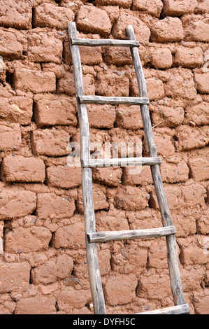 Ancienne échelle en bois reposant contre adobe altérés mur de briques séchées au soleil Banque D'Images