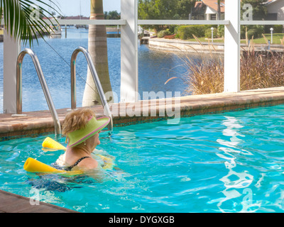 Femme mature se prélasser dans la piscine extérieure avec des nouilles, Florida, USA Banque D'Images