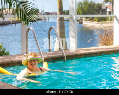 Femme mature se prélasser dans la piscine extérieure avec des nouilles, Florida, USA Banque D'Images