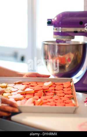 Mains tenant Heart-Shaped Cookies sur plaque avec mélangeur violet en arrière-plan Banque D'Images