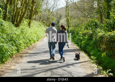 Un jeune couple en train de marcher un chien dans un chemin de campagne Banque D'Images