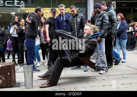 Manchester, UK. 19 avril 2014. Un jeune homme tente d'expliquer à ses amis la façon dont un artiste de rue défiant la gravité est en mesure de montrer son talent en face de passant en rue du marché. Artiste de rue Manchester, UK 19 avril 2014 Crédit : John Fryer/Alamy Live News Banque D'Images