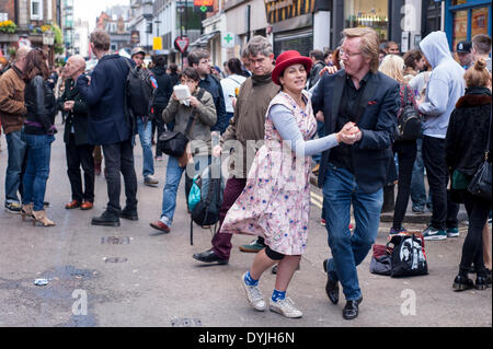 Berwick Street London, UK, 19 avril 2014. Record Store Day célèbre la culture unique entourant les propriétaires de magasins de disques. Le personnel, les clients et les artistes se réunissent pour reconnaître la culture unique d'un magasin de disques et le rôle spécial que ces magasins indépendants jouent dans leurs communautés. Vinyle et CD spécial presse et divers articles promotionnels sont faits exclusivement pour la journée. Un couple danse dans la rue à la musique de la scène. Crédit : Stephen Chung/Alamy Live News Banque D'Images