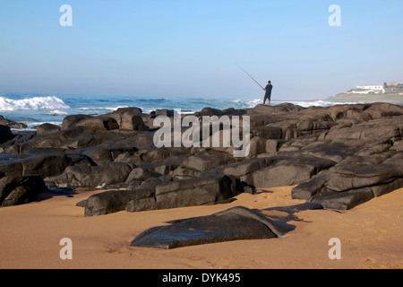 Pêcheur solitaire sur des pierres à plage de Ballito au nord de Durban en Afrique du Sud Banque D'Images