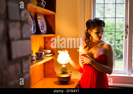 Jeune femme dans une orange, sans bretelles robe de soirée en face d'une vieille commode. Banque D'Images