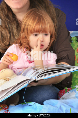 Petite fille rousse écouter une histoire Choisir son nez Banque D'Images