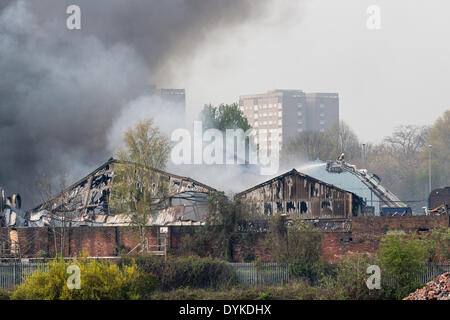 Leeds, West Yorkshire, Royaume-Uni, 21 avril 2014. Un pompier dirige l'eau sur un incendie dans une zone industrielle de Leeds. L'incendie a éclaté à environ 1,50 heures dans les locaux d'Tradpak une usine de recyclage de l'emballage et de produits chimiques dans l'Armley de la ville. L'usine est à proximité du centre-ville et les résidants des environs ont été dit de garder leurs fenêtres et portes fermées à cause de produits chimiques potentiellement toxiques impliqués. Crédit : Ian Wray/Alamy Live News Banque D'Images