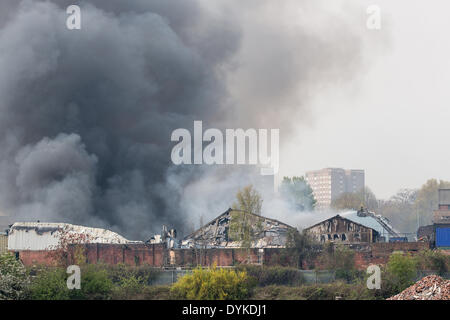 Leeds, West Yorkshire, Royaume-Uni, 21 avril 2014. Un pompier dirige l'eau sur un incendie dans une zone industrielle de Leeds. L'incendie a éclaté à environ 1,50 heures dans les locaux d'Tradpak une usine de recyclage de l'emballage et de produits chimiques dans l'Armley de la ville. L'usine est à proximité du centre-ville et les résidants des environs ont été dit de garder leurs fenêtres et portes fermées à cause de produits chimiques potentiellement toxiques impliqués. Crédit : Ian Wray/Alamy Live News Banque D'Images