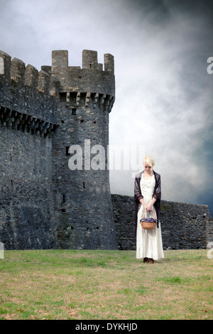 Une femme dans une période blanche robe est debout en face d'un château Banque D'Images