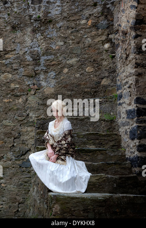 Une dame dans une période blanche robe est assis sur des marches en pierre ancienne Banque D'Images