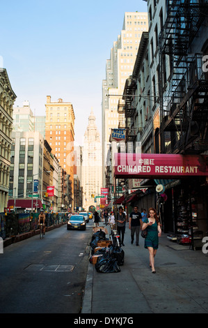 Une femme marche et à la recherche au téléphone dans le quartier chinois, une scène de rue à New York City. Banque D'Images