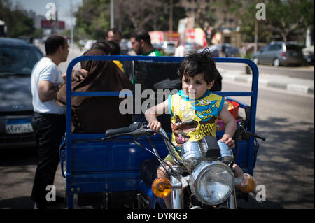 Le Caire, Égypte. Apr 21, 2014. Un enfant égyptien se trouve sur la place de conduite d'un tricycle à moteur alors qu'il célèbre avec sa famille la fête traditionnelle ham 'el-Nessim', littéralement traduit comme 'Smell le Breeze", également connu sous le nom de festival du printemps, au Caire, capitale de l'Égypte, le 21 avril 2014. Source : Xinhua/Chaoyue Pan/Alamy Live News Banque D'Images