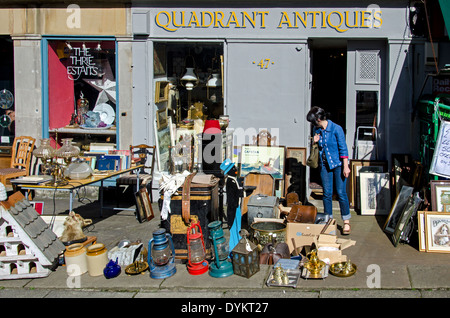 Une jeune femme de la navigation entre les le bric-à-brac sur le trottoir devant une boutique d'antiquités dans la nouvelle ville d'Édimbourg. Banque D'Images