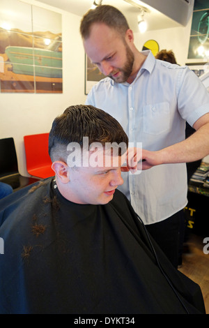 Teenage boy avoir couper les cheveux dans une boutique de barbier Banque D'Images