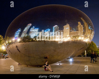 Une jolie fille brune au-dessous de Cloud Gate (le Bean) sur une nuit d'été à Millennium Park, Chicago, Illinois. Banque D'Images