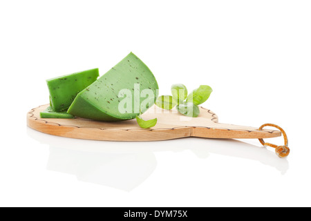 Fromage de gouda vert luxueux sur la planche à découper ronde en bois isolé sur fond blanc avec la réflexion. Fromages culinaires Banque D'Images