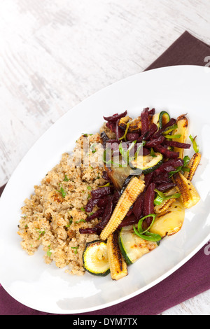 Couscous aux légumes frits sur plaque blanche sur fond texturé en bois blanc. L'alimentation végétarienne culinaire. Banque D'Images