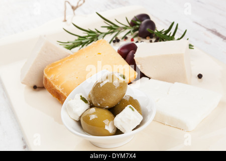 Différents fromages, olives noires, romarin et poivre cuisine colorée sur le fond en bois blanc. Manger culinaire Banque D'Images