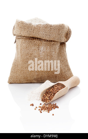 La farine dans un sac brun et le sarrasin dans scoop en bois isolé sur fond blanc. Banque D'Images