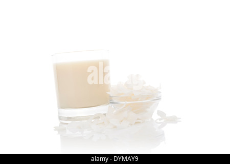 Le lait de coco dans le verre avec des flocons de noix de coco on white background, studio isolé. La cuisine asiatique culinaire ingrédient. Banque D'Images