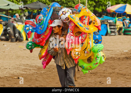 Relations sérieuses in gonflable en plastique vendeur des marchandises sur la plage de la ville de cette importante station balnéaire sur la côte sud, Pangandaran, Java, Indonésie Banque D'Images