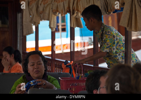 Portrait d'un horizontal dame asiatique l'achat des collations à partir d'un garçon sur un slowboat le Mékong. Banque D'Images