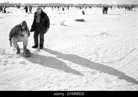 Pêcheur sur glace en concours de pêche sur le lac de la forêt, MN. Banque D'Images