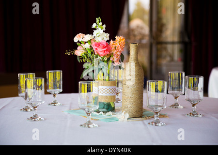 Bricolage Décoration mariage centres de table avec des bouteilles de vin enveloppé dans de la toile de jute et de ficelle rose flowers. Banque D'Images