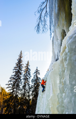 D'alpiniste qui monte à pente enneigée de haches Banque D'Images