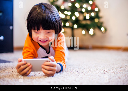 Mixed Race boy playing with smart phone in living room Banque D'Images