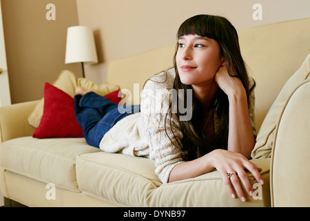 Mixed Race woman laying on sofa Banque D'Images