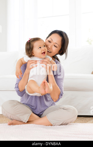 Mère jouant avec baby girl in living room Banque D'Images