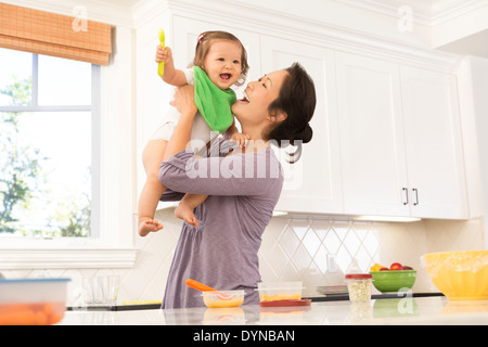 Mother holding baby girl in kitchen