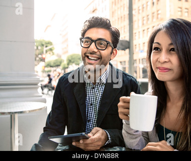 Couple enjoying coffee at sidewalk cafe Banque D'Images