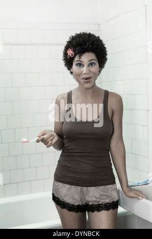 Femme se brosser les dents dans la salle de bains Banque D'Images
